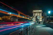 Long-exposure night photograph of Budapest's Chain Bridge with colorful light trails from passing traffic,