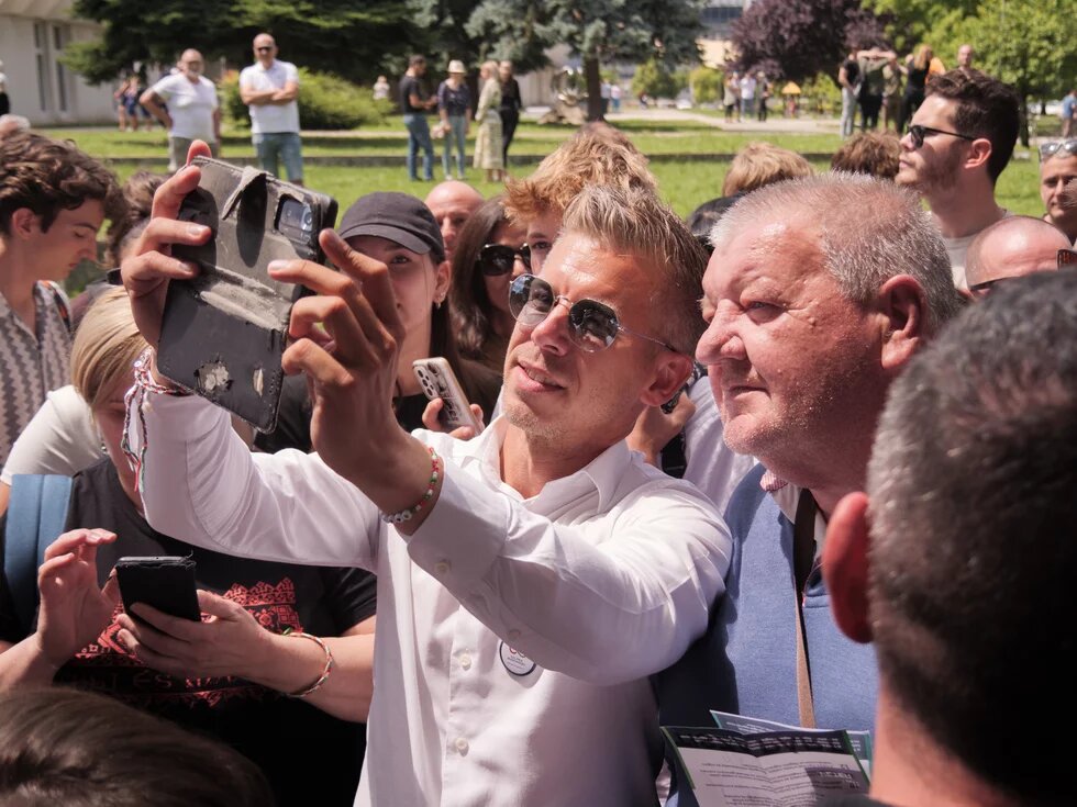 Peter Magyar takes a selfie with a man among the people. A political countrywide tour event by the Tisza Party. 2024